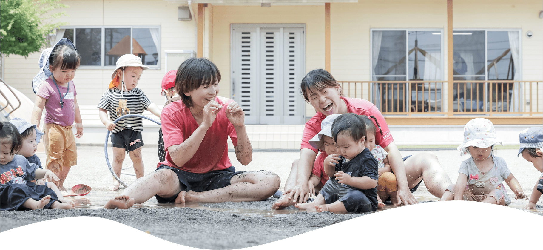 泥で遊ぶ子ども達と2人の先生