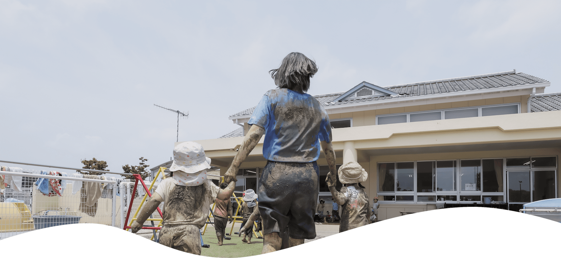 全身泥まみれの先生と2人の子どもの背中