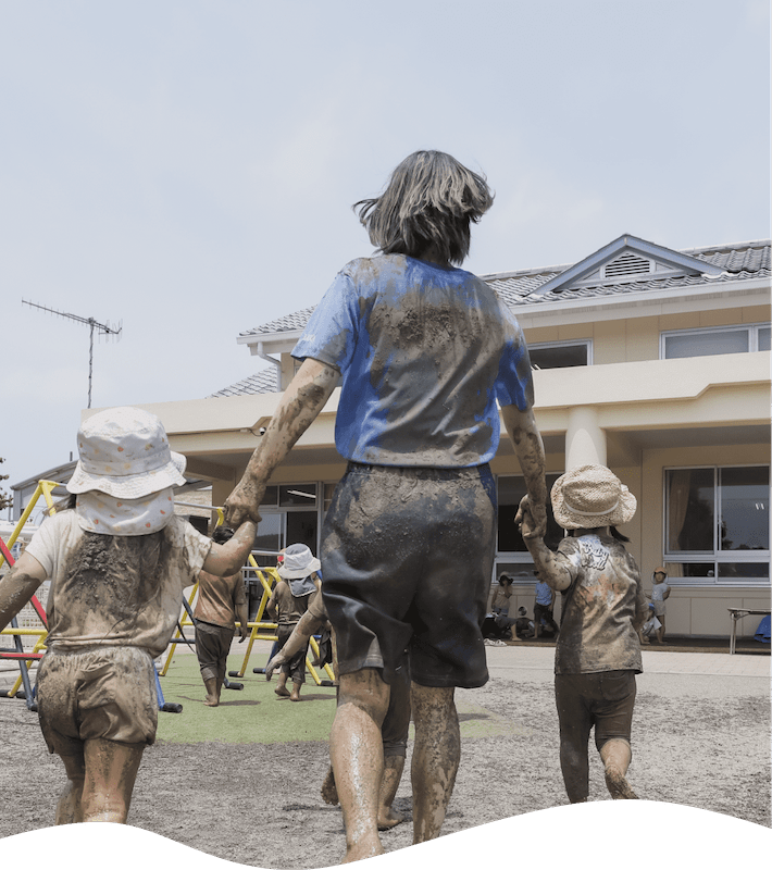 全身泥まみれの先生と2人の子どもの背中